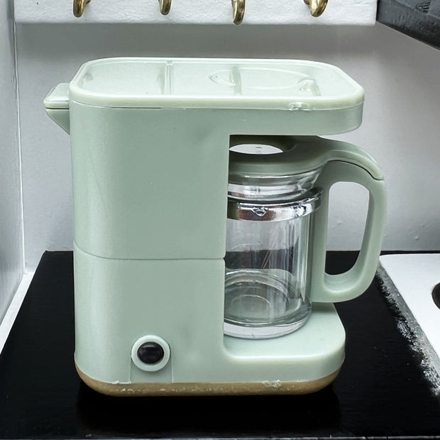 a green coffee maker sitting on top of a counter