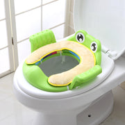 a green frog potty seat sitting on top of a toilet