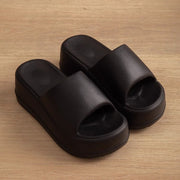 a pair of black slippers sitting on top of a wooden floor